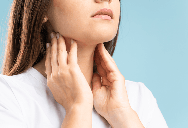 Lady holding her neck because she has a sore throat